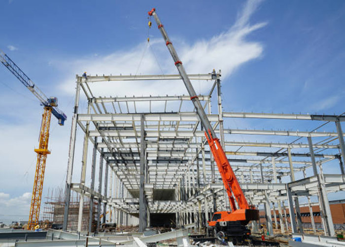 Construcción de estructura de estructura de acero instalación de marco de armadura de techo por grúa móvil bajo el edificio de construcción en la fábrica con cielo azul